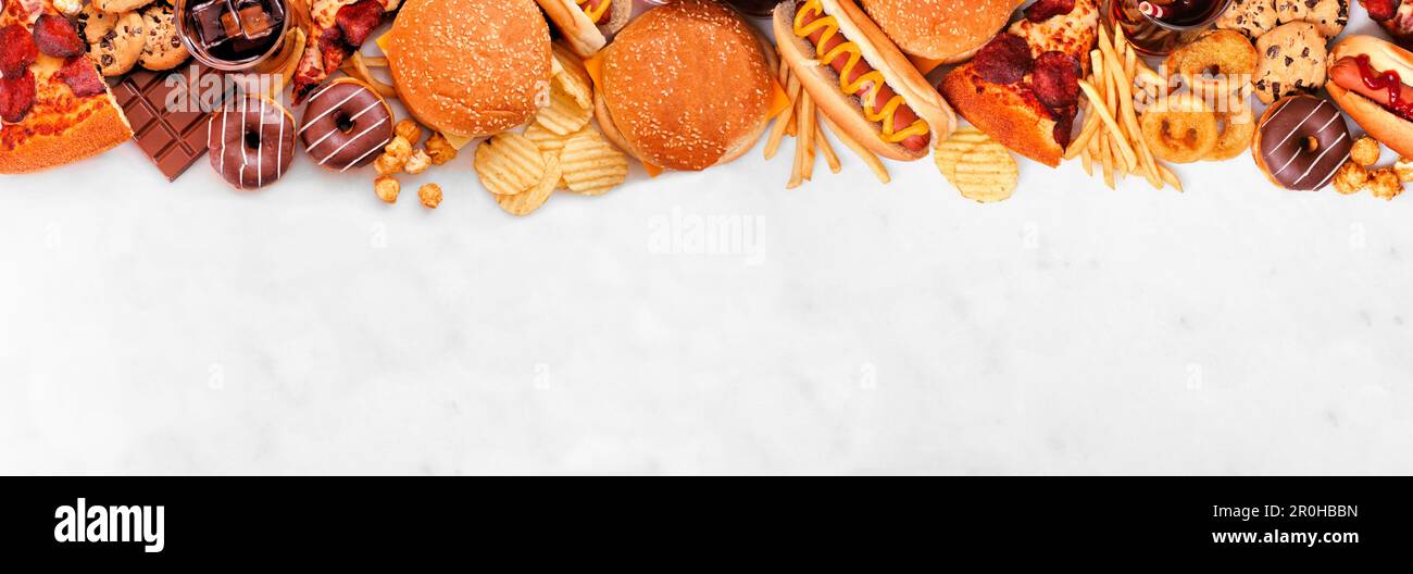 Il bordo superiore del cibo spazzatura sopra uno sfondo di bandiera di marmo bianco. Selezione di piatti da portare fuori e fast food. Pizza, hamburger, patatine fritte, patatine, hot dog, int Foto Stock
