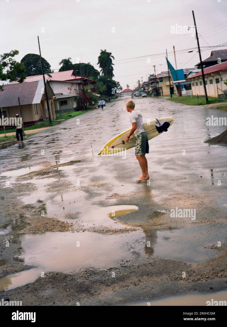 PANAMA, Bocas del Toro, un surfista passeggiate attraverso il centro della città sotto la pioggia, America Centrale Foto Stock
