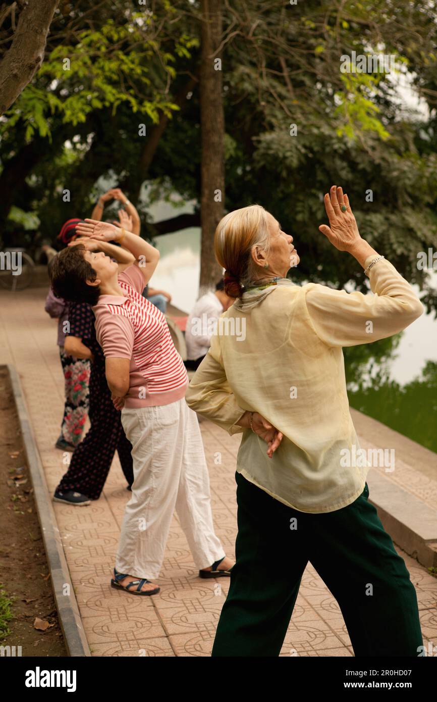 Il Vietnam, Hanoi, donne praticare il tai chi al mattino presto, il Lago Hoan Kiem Foto Stock