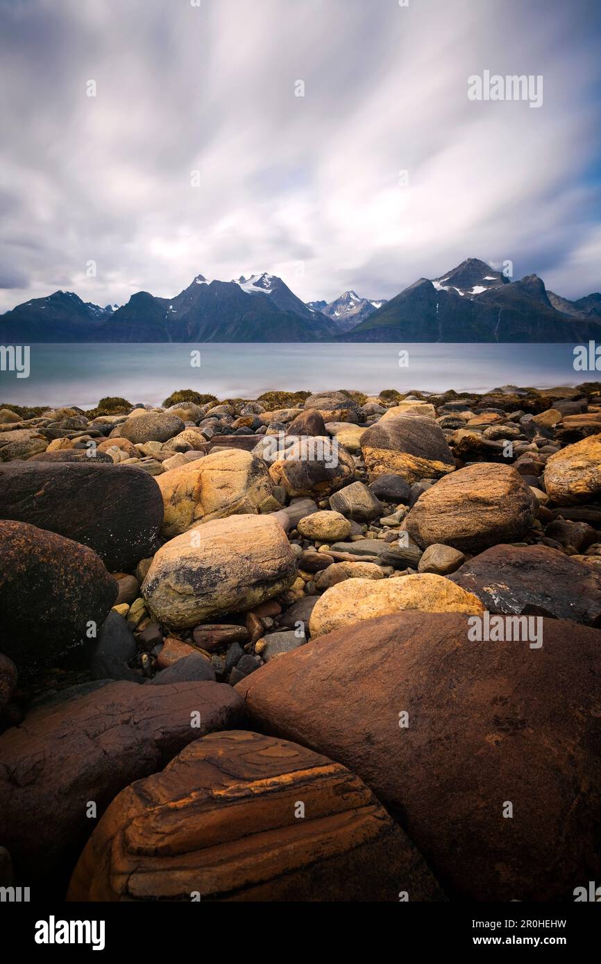 Lunga esposizione sul fiordo di Lyngen con le cime innevate delle Alpi di Lyngen sullo sfondo, Troms, Norvegia Foto Stock