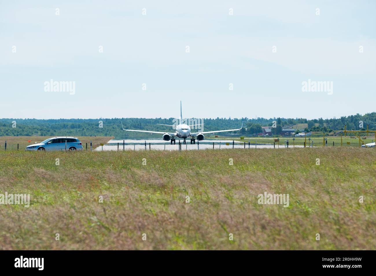 Un Boeing 737 in un piccolo aeroporto, una strada con un'auto in primo piano Foto Stock