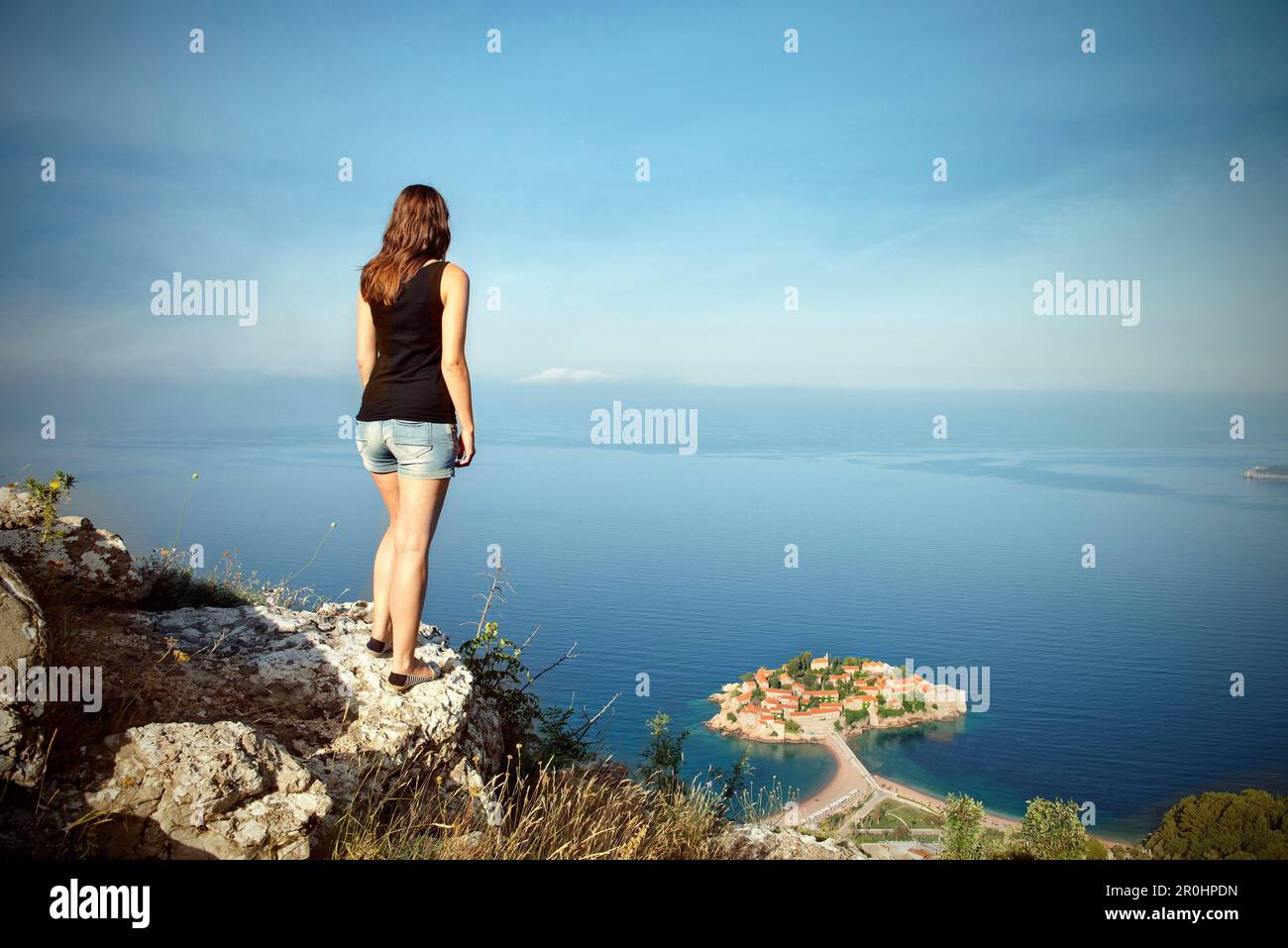 Giovane donna che gode di una vista panoramica del lussuoso Hotel Island Sveti Stefan, costa adriatica, Montenegro, Balcani occidentali, Europa Foto Stock