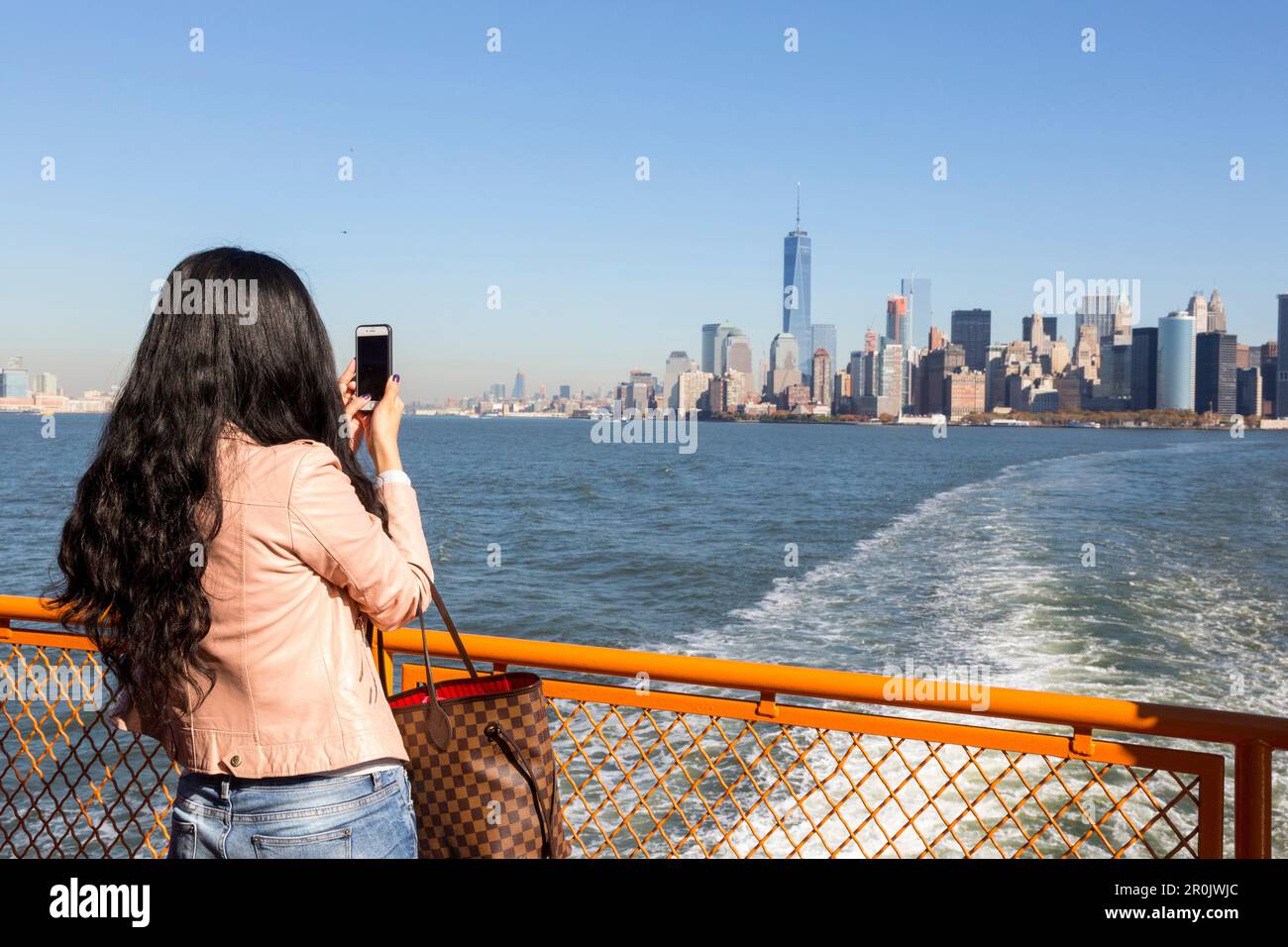 Donna asiatica con scattare foto con il suo cellulare, telefono cellulare, traghetto per Staten Island, vista sul Hudson al centro di Manhattan e la nuova Foto Stock