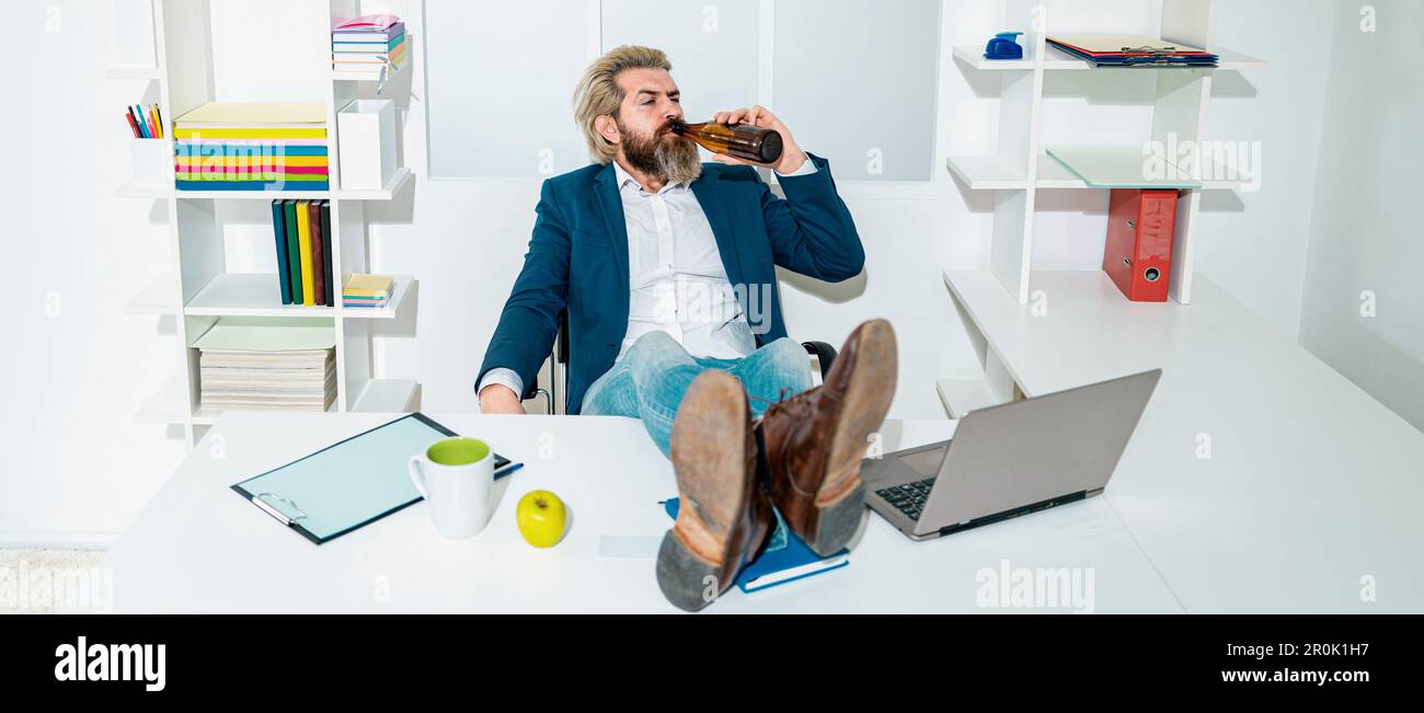 Un uomo d'affari ubriaco annoiato in ufficio alla fine della giornata lavorativa. Uomo d'affari ubriaco con una bottiglia di alcol. Lavoratore ubriaco in ufficio, trasportando casualmente una bottiglia Foto Stock