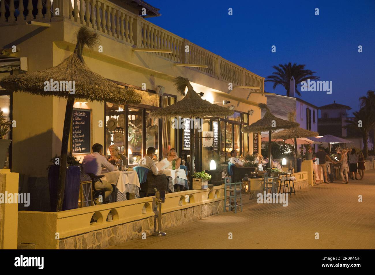Le persone si siedono all'aperto e si gustano la cena al ristorante SA Xarxa sul lungomare al crepuscolo, Colonia de Sant Pere, Maiorca, Isole Baleari, Spagna Foto Stock