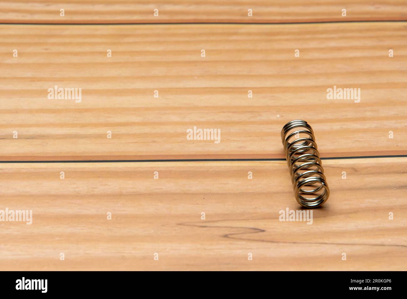Molla o molla a spirale sul bordo dell'immagine con spazio libero sul testo sulla base in legno Foto Stock