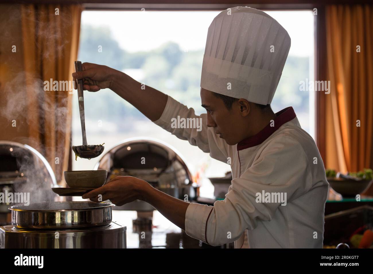 Lo chef riempie la zuppa durante il pranzo a bordo di Ayeyarwady (Irrawaddy) nave da crociera sul fiume Anawrahta (Heritage Line), vicino a Kyauk Myaung, Sagaing, Myanmar Foto Stock