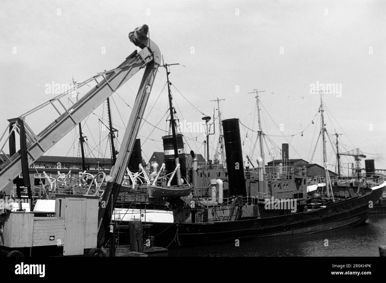 Fischkutter im Fischereihafen Cuxhaven, die alte Netzhalle im Hintergrund, 1960. Pescatore nel porto di pesca di Cuxhaven, la vecchia sala delle reti sullo sfondo, 1960. Foto Stock