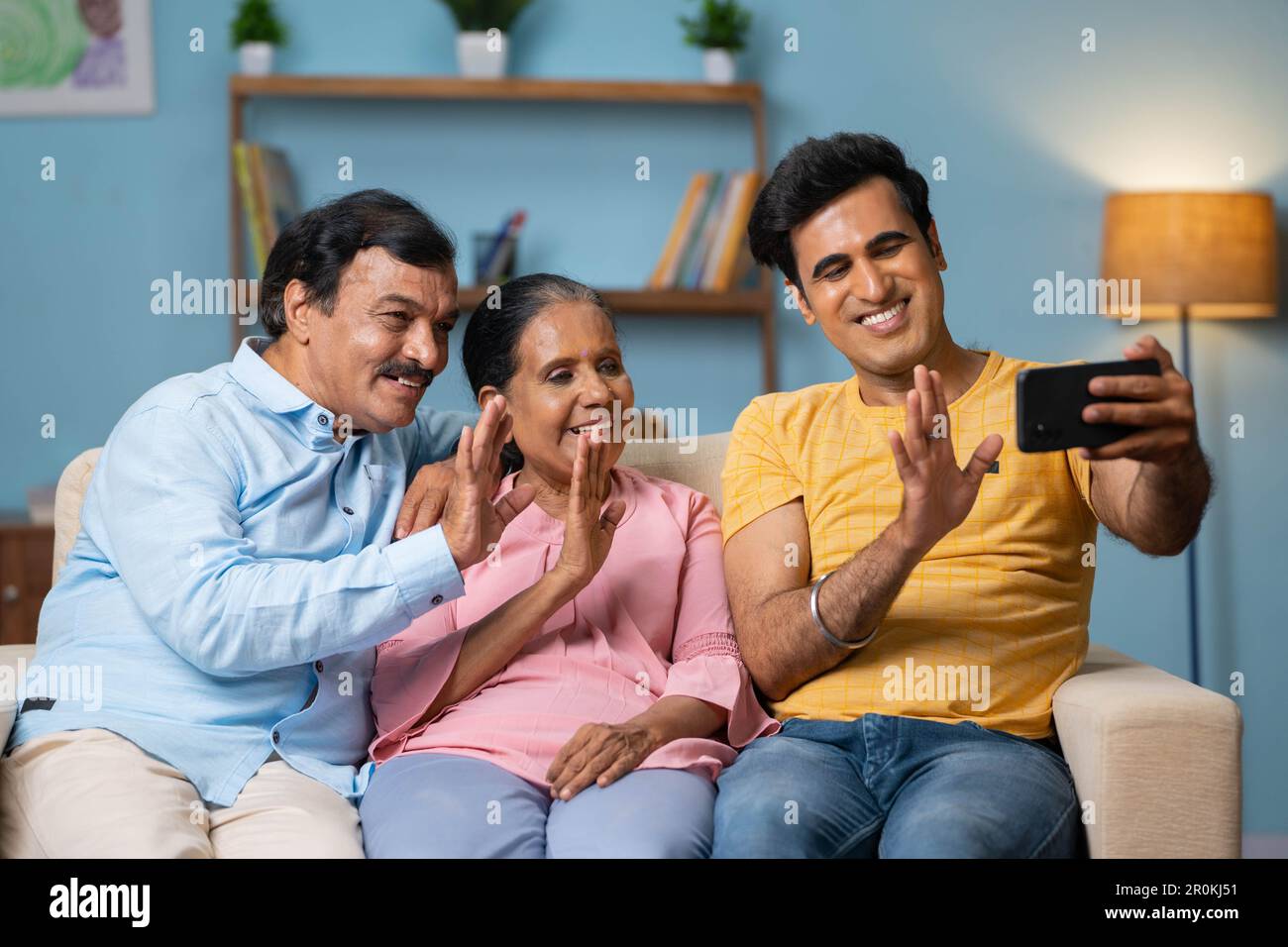 Felice sorridente indiano anziani genitori con figlio adulto che effettua  la videochiamata sul telefono cellulare mentre si siede sul divano a casa -  concetto di tecnologia, famiglia Foto stock - Alamy