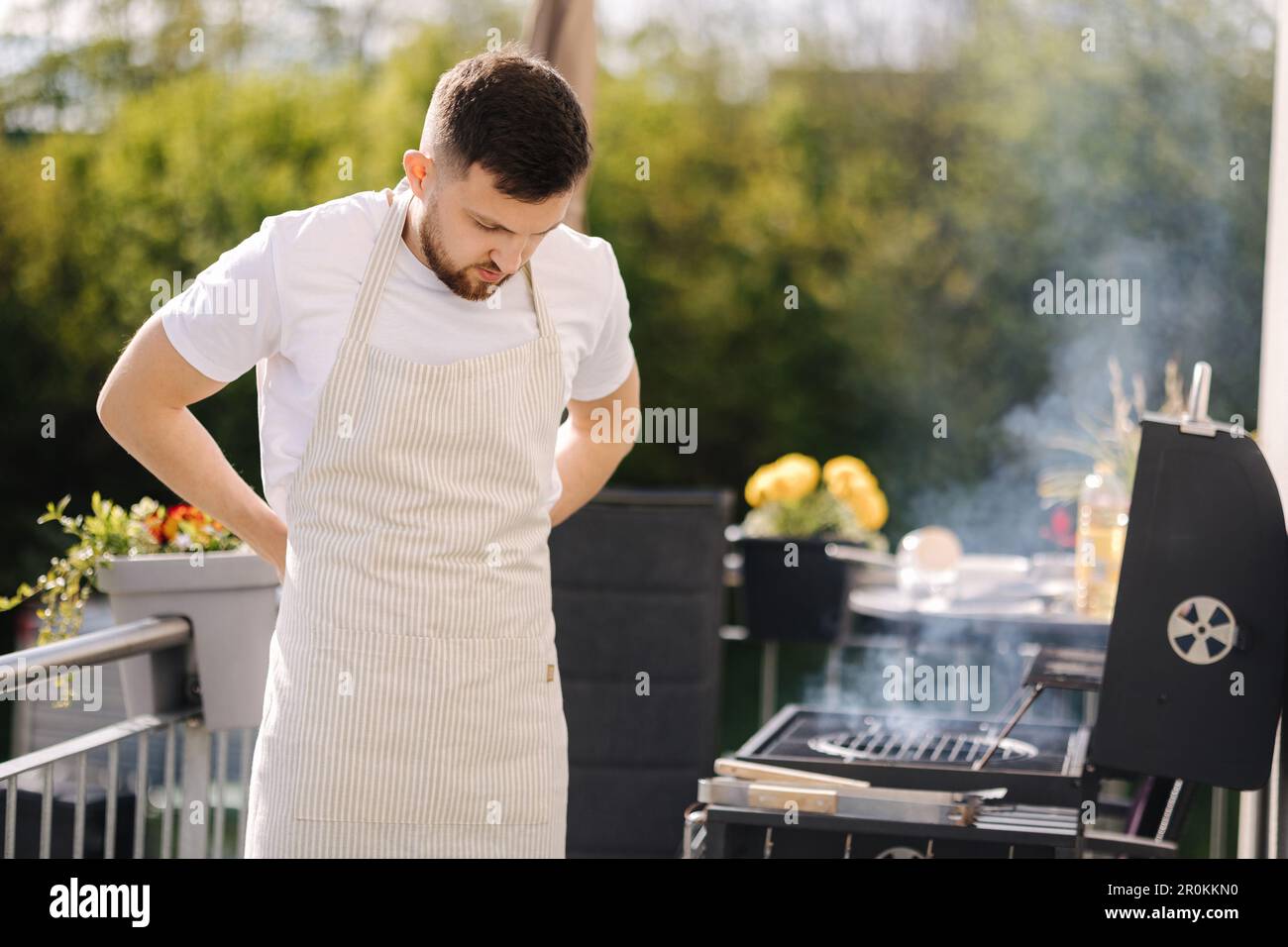 Uomo mette su un grembiule all'aperto. Preparazione per il barbecue Foto Stock