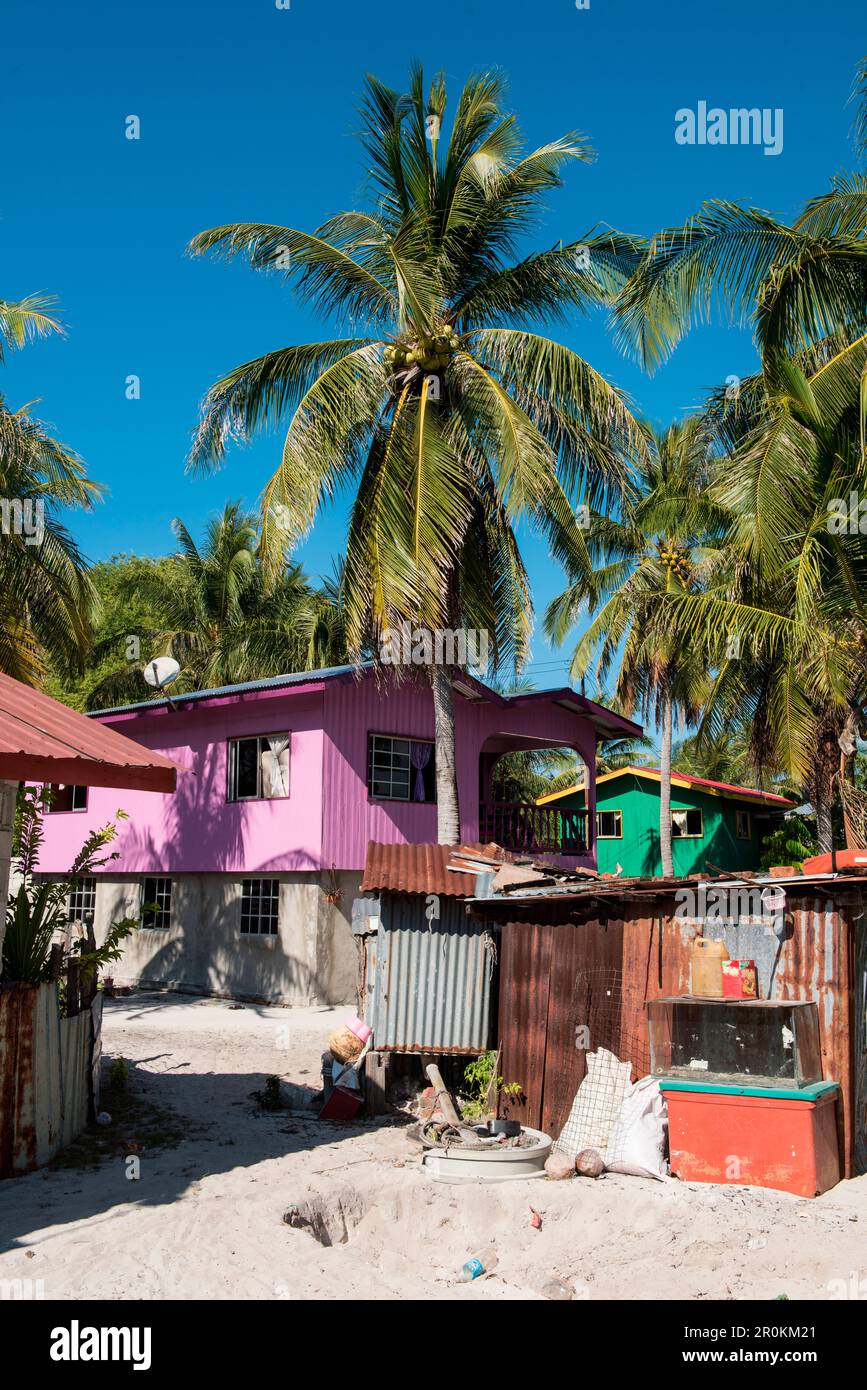 Una casa di legno a due piani dipinta con colori luminosi contrasta con una baracca di latta corrugata in un villaggio di pescatori, Pulau Mantanani, Isole Mantanani, vicino Sabah, Foto Stock