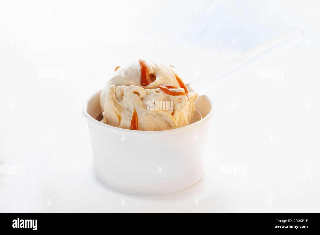 Gelato al cioccolato bianco al caramello alla vaniglia in una tazza di carta senza marchio con cucchiaio di plastica. Foto Stock