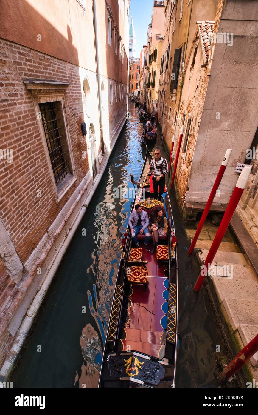 Vista panoramica di una linea di gondole in uno stretto canale di Venezia Foto Stock