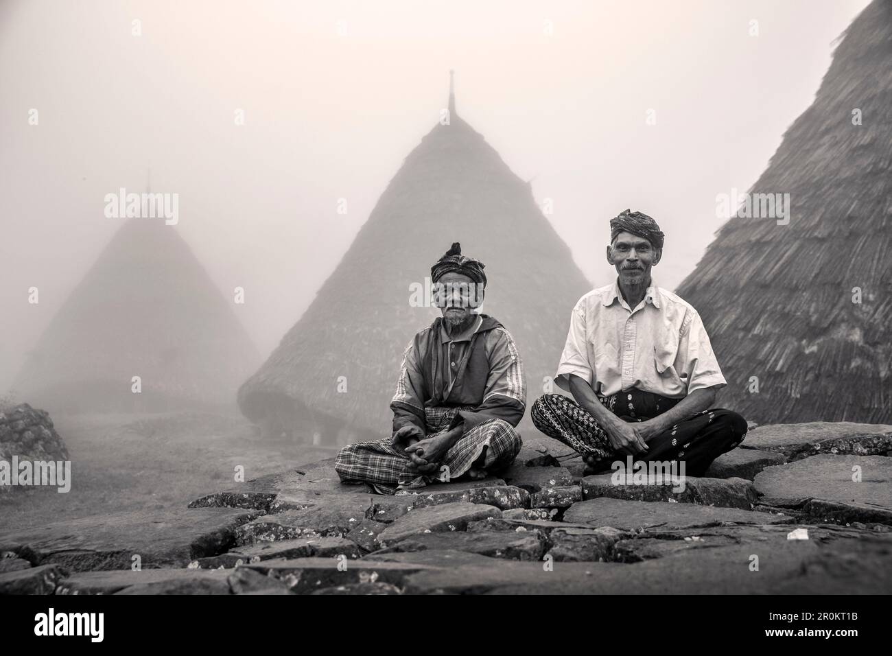 INDONESIA, Flores, due leader della Wae Rebo Village sedersi di fronte a loro residenze chiamato Mbaru Niang Foto Stock