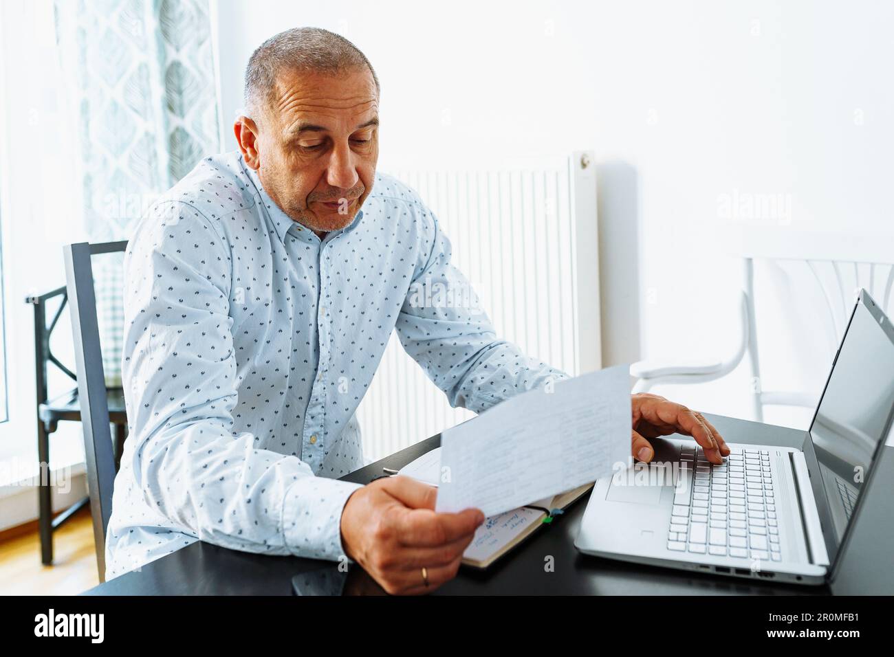l'uomo fa i calcoli, guarda attraverso il rapporto finanziario del registratore di cassa domestico Foto Stock