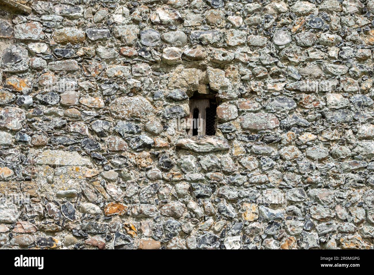 Finestra in legno senza vetro molto piccola e parete in selce di prestigio presso la Chiesa di San Pietro a Weston, Suffolk Foto Stock