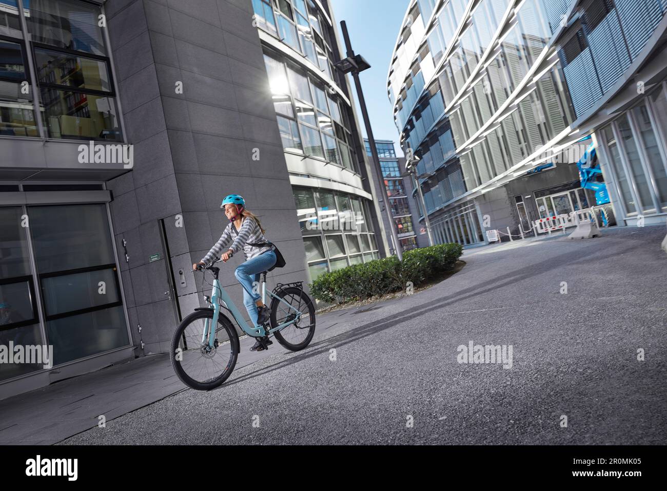 Giovane donna in bicicletta in ambiente urbano, Monaco, Baviera, Germania Foto Stock