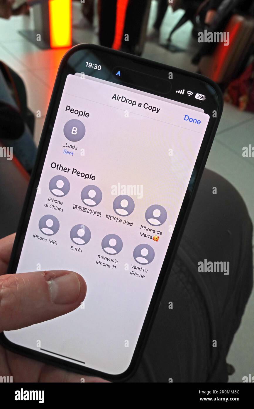 Pericoli di condividere un'immagine utilizzando AirDrop trasferimento in un luogo pubblico, come un aeroporto, a telefoni stranieri vicini. Foto Stock