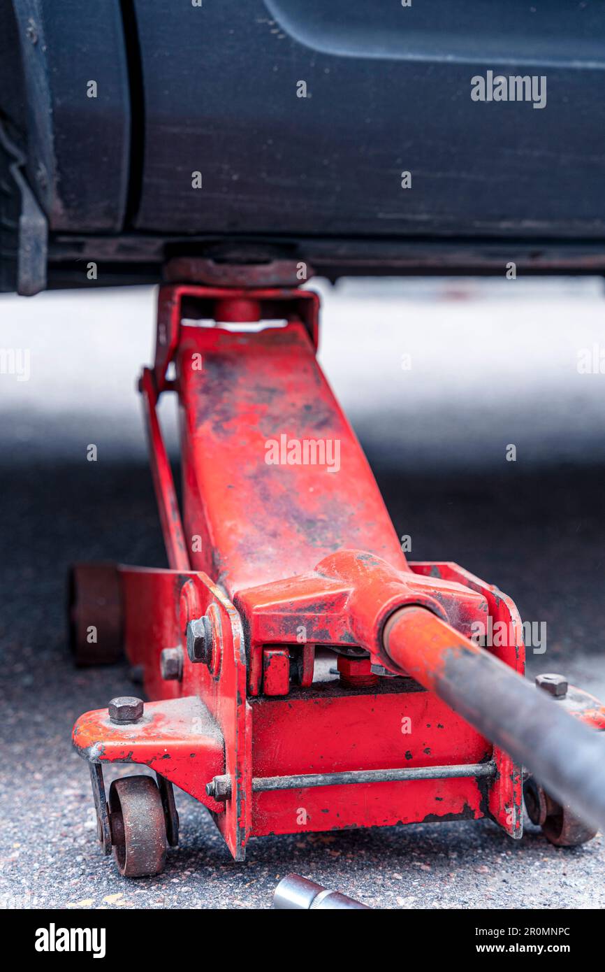 sostituzione delle ruote per auto. sollevare il veicolo con l'elp del martinetto idraulico. Foto Stock