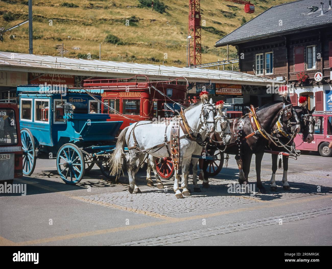 Scena di strada nella località alpina svizzera di Zermatt, qui si vede con carrozze trainate da cavalli fuori dalla stazione ferroviaria di Zermatt Foto Stock