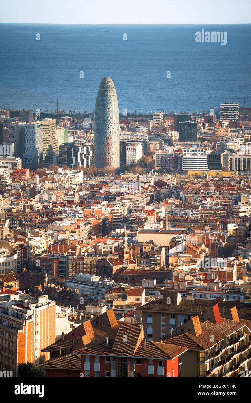 Vista aerea della moderna e alta torre Agbar situata tra edifici residenziali e grattacieli vicino al mare nella soleggiata città di Barcellona Foto Stock
