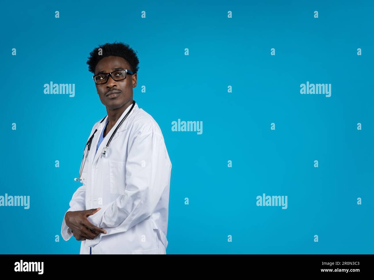 Medico afro-americano sicuro che indossa gli occhiali, sfondo blu Foto Stock