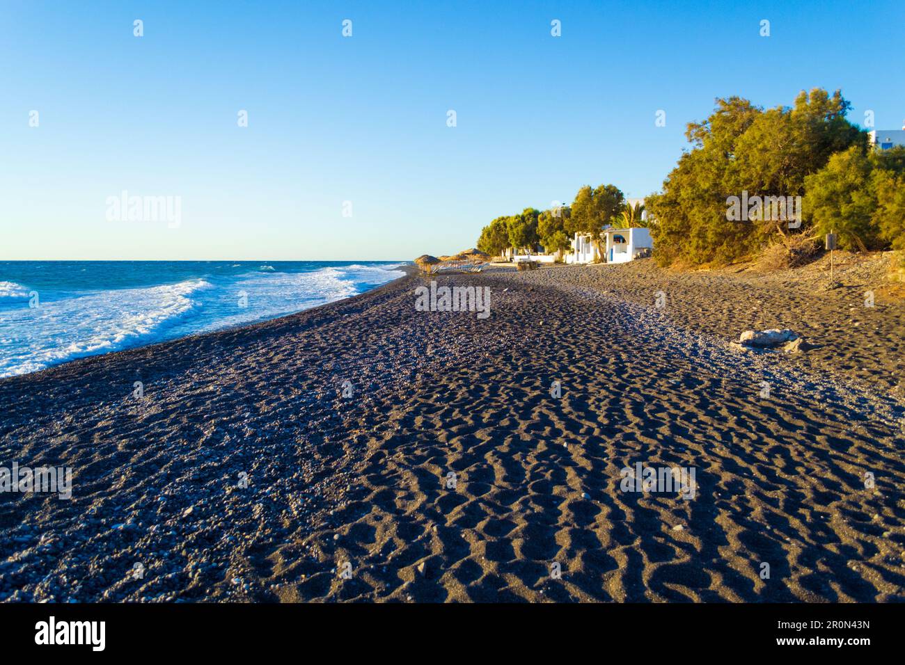 Le ville in ciottoli neri e sulla spiaggia di Avis Beach. Si trova vicino all'estremità meridionale dell'aeroporto internazionale di Santorini, Kamari, Grecia Foto Stock