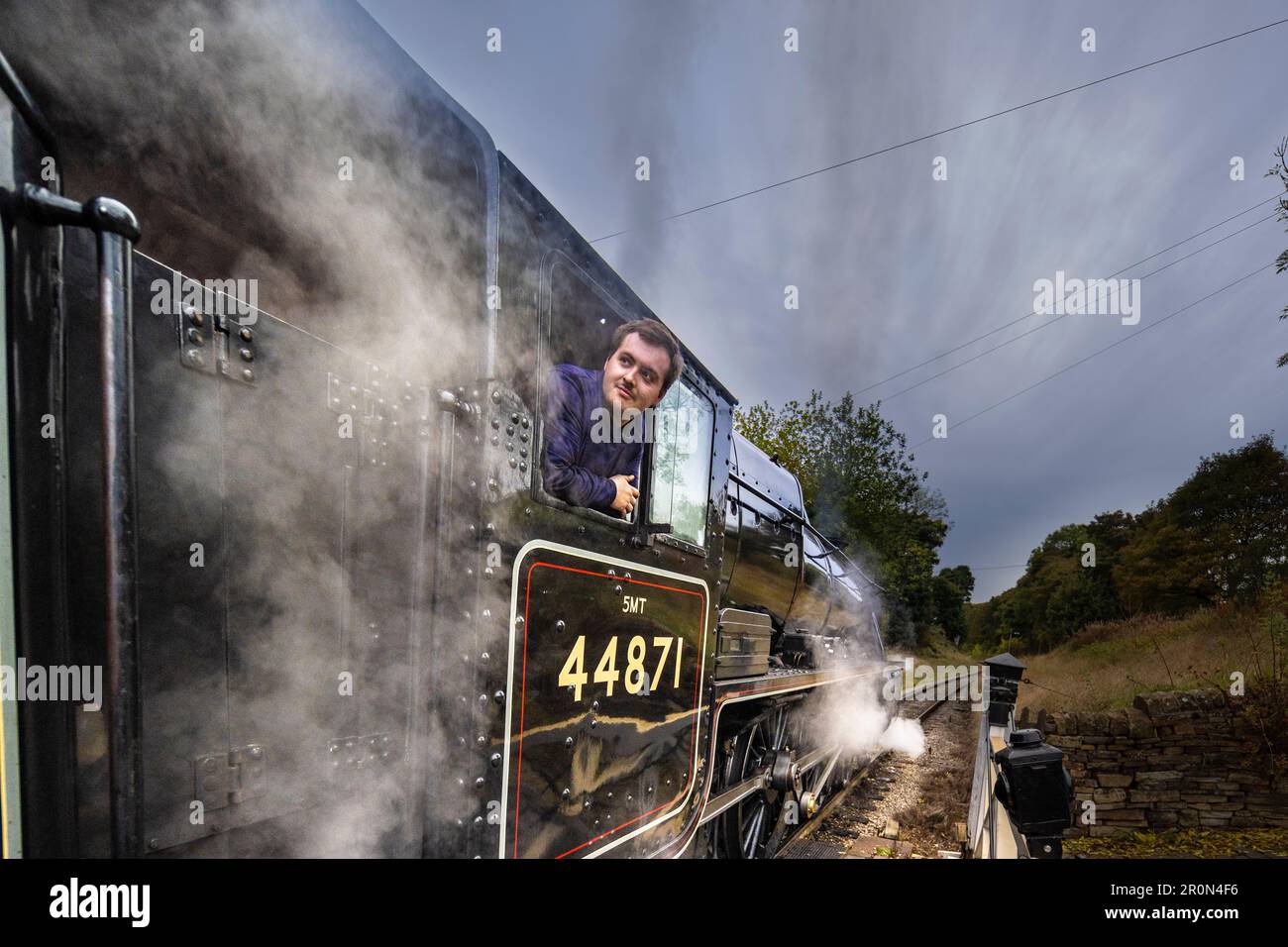 Autista del treno, in attesa della bandiera verde per partire dalla stazione ferroviaria di Haworth. Foto Stock