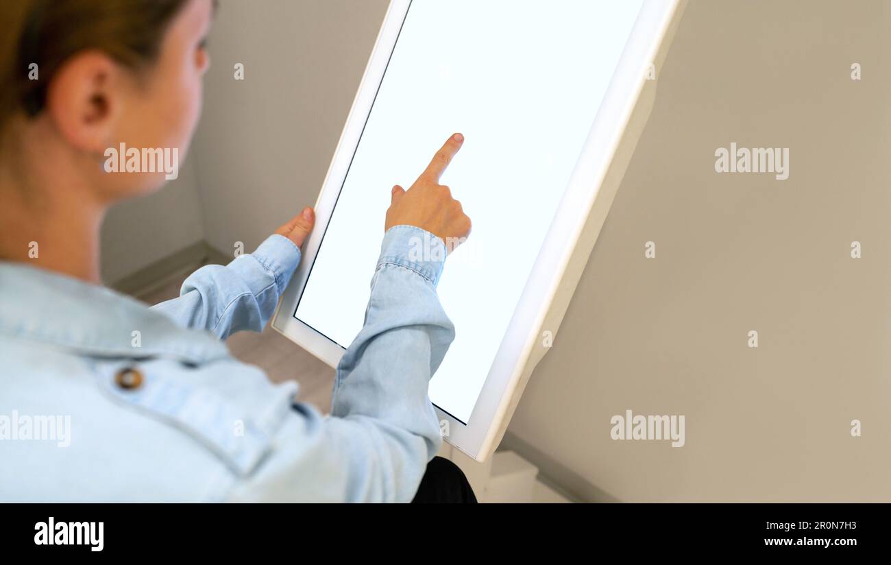 Donna che utilizza il touch screen digitale per il check-in automatico. Foto Stock