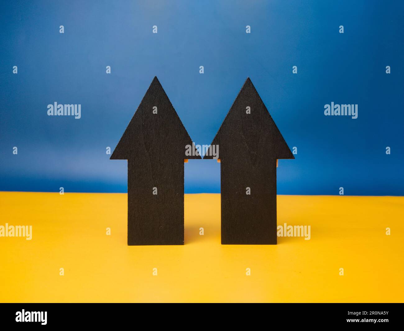 Due frecce di carta nera che puntano su uno sfondo blu e giallo Foto Stock