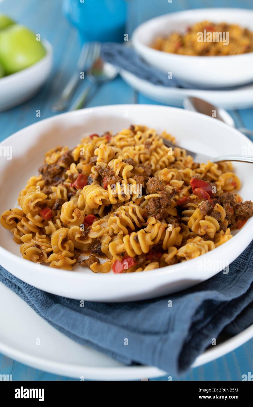 Piatto di pasta con carne macinata, pomodori, peperoni, cipolle ed erbe su un piatto Foto Stock
