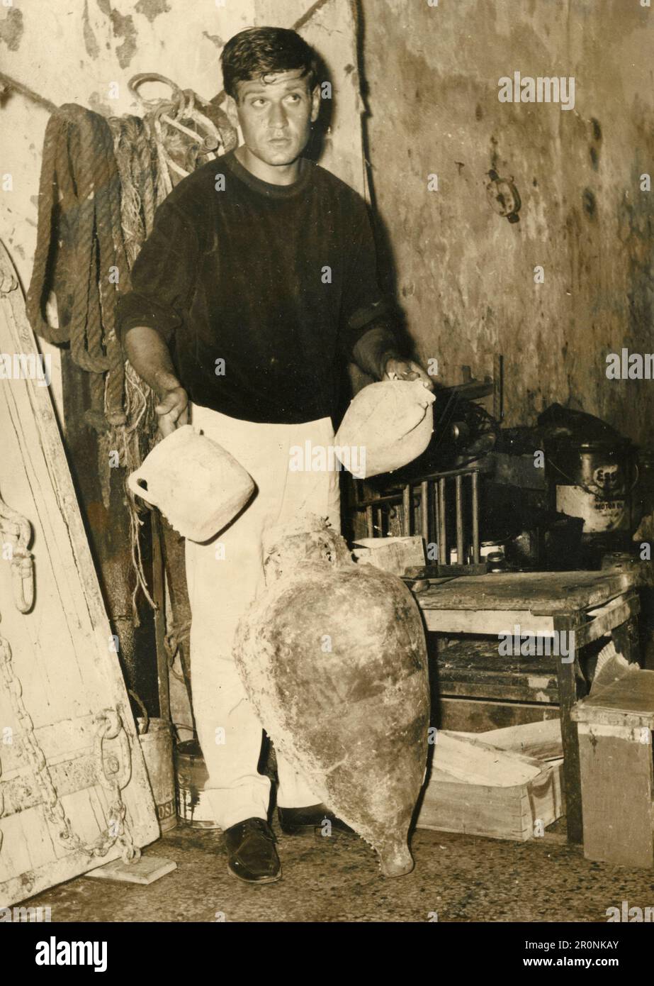 Uomo che mostra antichi vasi e anfora trovato sott'acqua, Italia 1965 Foto Stock