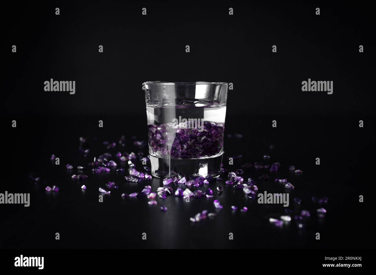 patatine ametista in un bicchiere d'acqua con fondo nero. gemma di guarigione, strega moder Foto Stock