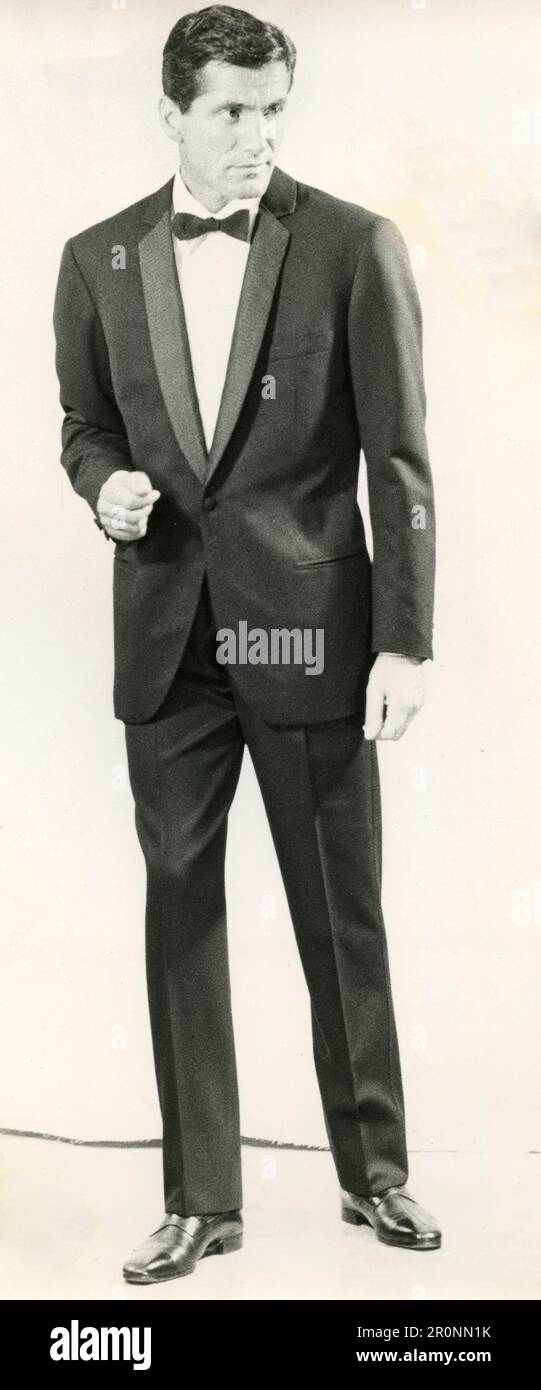 Modello uomo di moda con smoking tuxedo nero e lapelle in seta maroon fantasia dello stilista italiano Brioni, 1966 Foto Stock