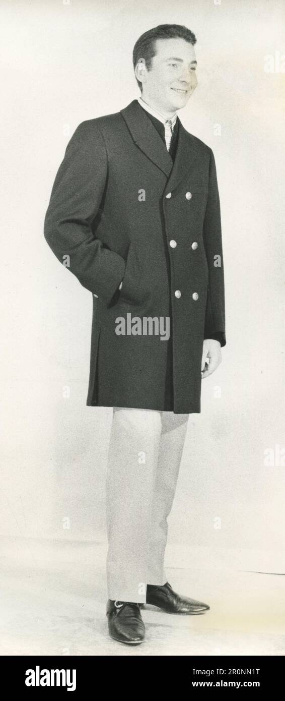 Modella moda uomo che indossa un cappotto per auto sportive in lana cotelè nera del designer italiano Brioni, 1966 Foto Stock