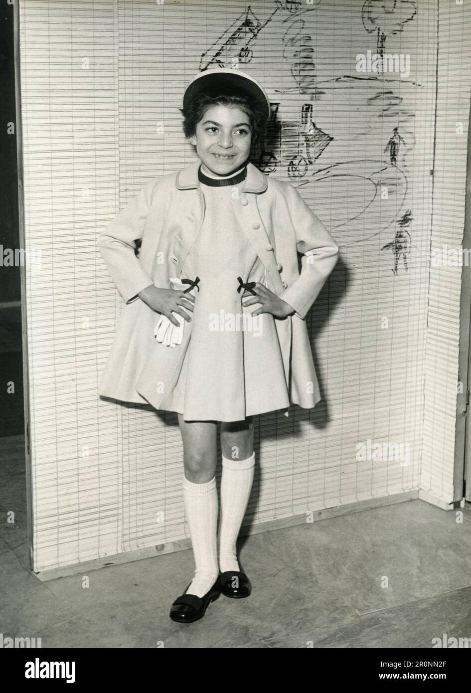 Moda per bambini: Modello che indossa un cappotto sopra un vestito, Italia 1966 Foto Stock
