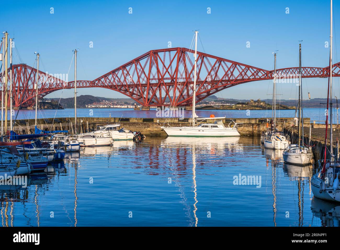 Barche ormeggiate nel porto di South Queensferry con lo sfondo di Forth Rail Bridge - South Queensferry, Scozia, Regno Unito Foto Stock