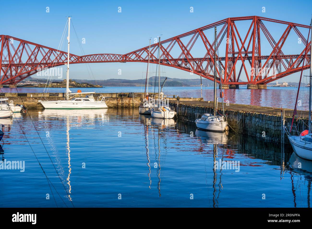 Barche ormeggiate nel porto di South Queensferry con lo sfondo di Forth Rail Bridge - South Queensferry, Scozia, Regno Unito Foto Stock