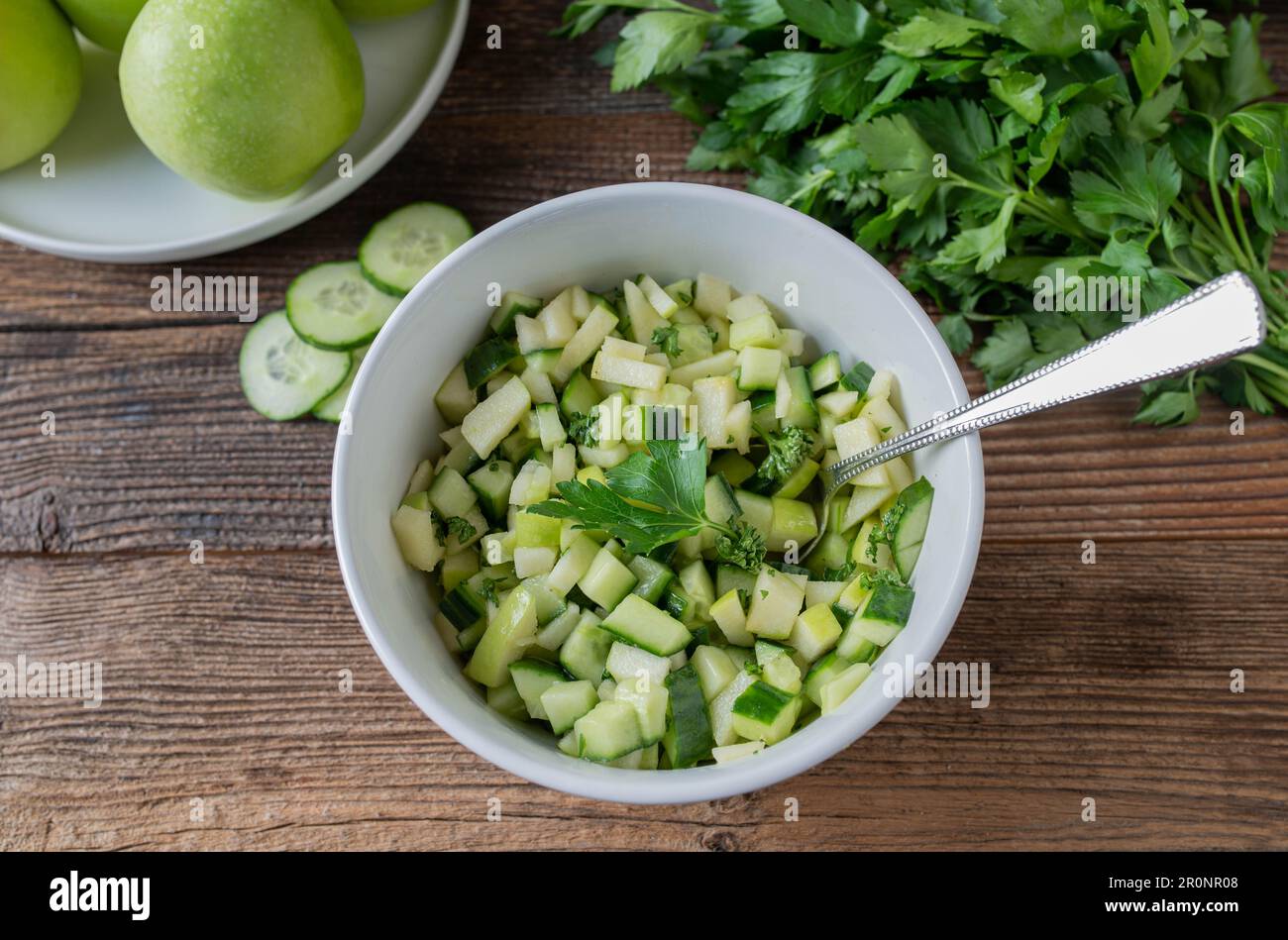 Insalata di frutta con mele verdi marinate e cetriolo in una ciotola su un tavolo di legno Foto Stock