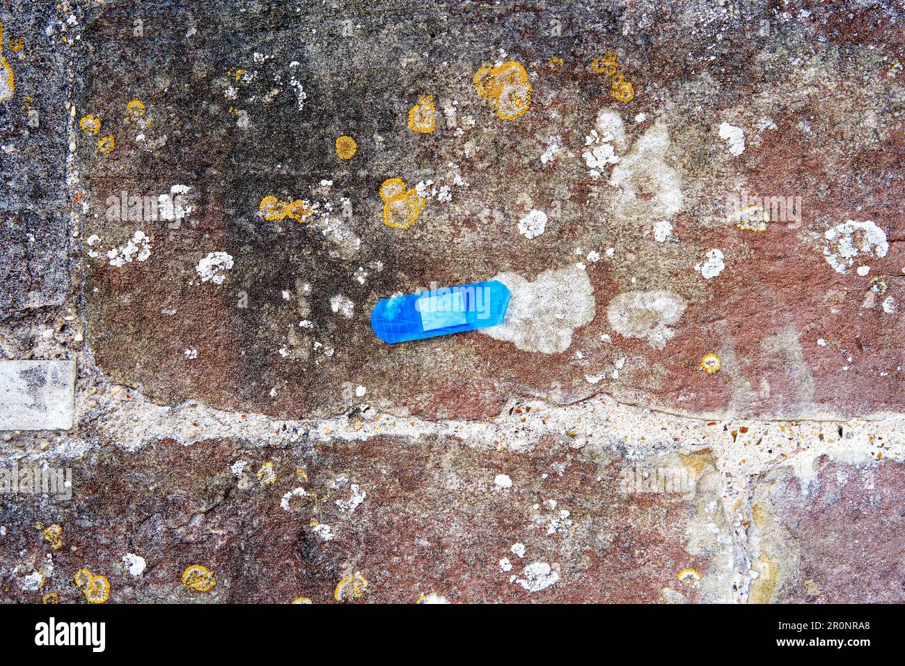 Cerotto di pronto soccorso blu incollato su un vecchio muro di pietra Foto Stock