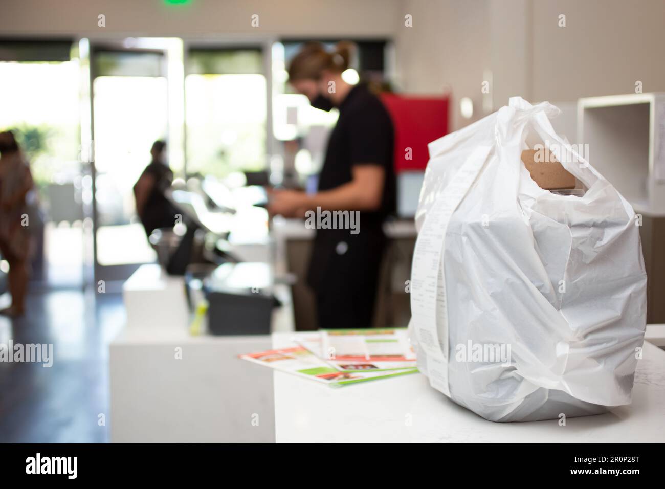 Una vista di un sacchetto di plastica da portare con se pieno di ordini di cibo da portare con se, visto su un banco di ristorante. Foto Stock