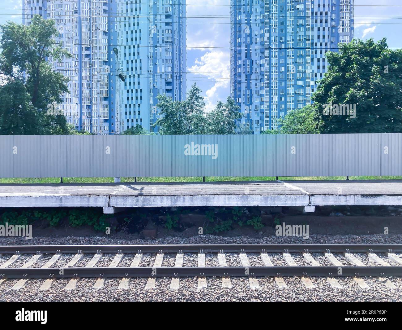 Splendida vista del centro città con il treno di passaggio. binari ferroviari, treni ad alta velocità, recinzione, case blu spazio per il testo Foto Stock