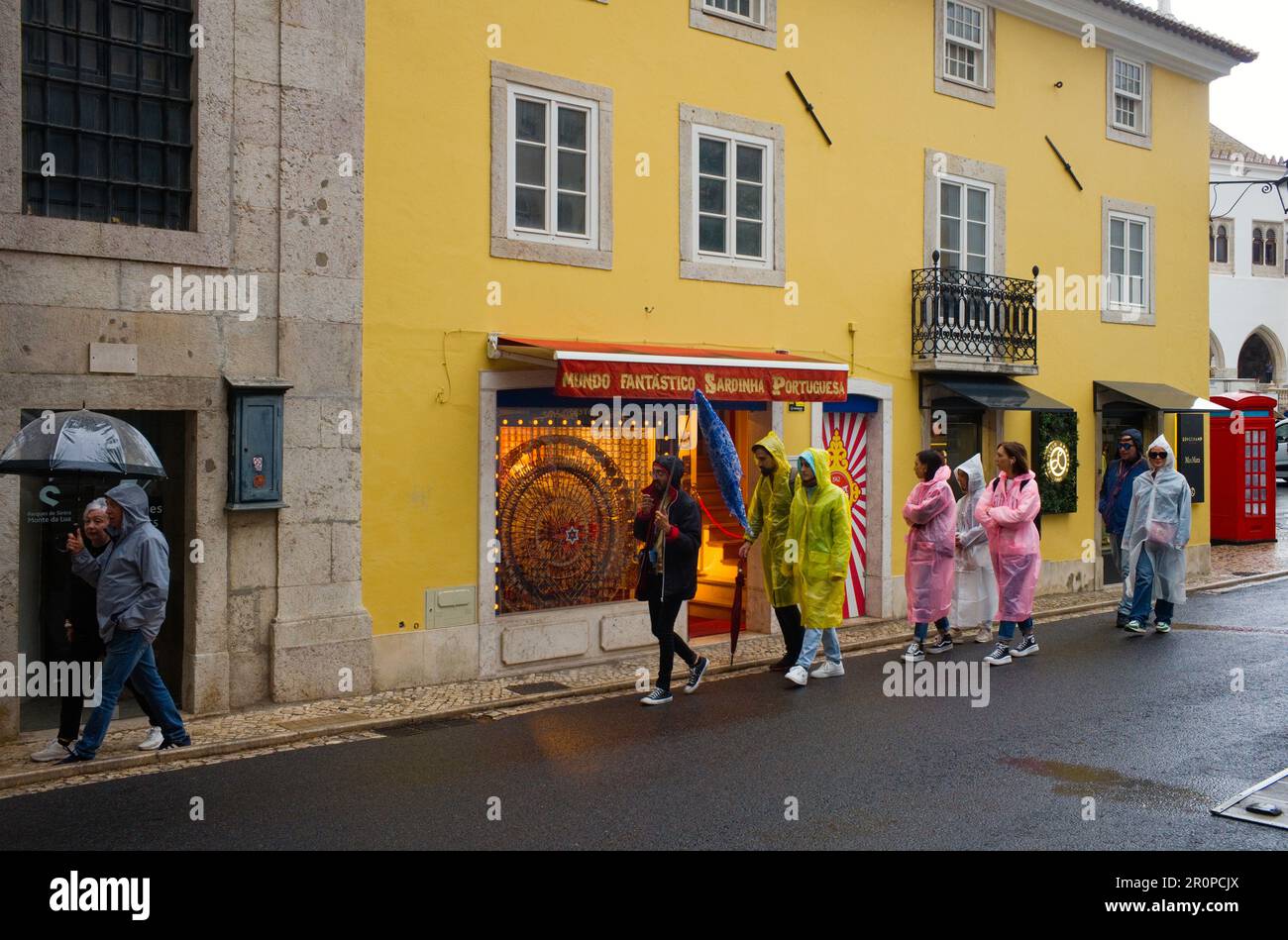 I turisti che indossano Mac in plastica per la pioggia vengono guidati in giro per Sintra in una mattinata bagnata Foto Stock
