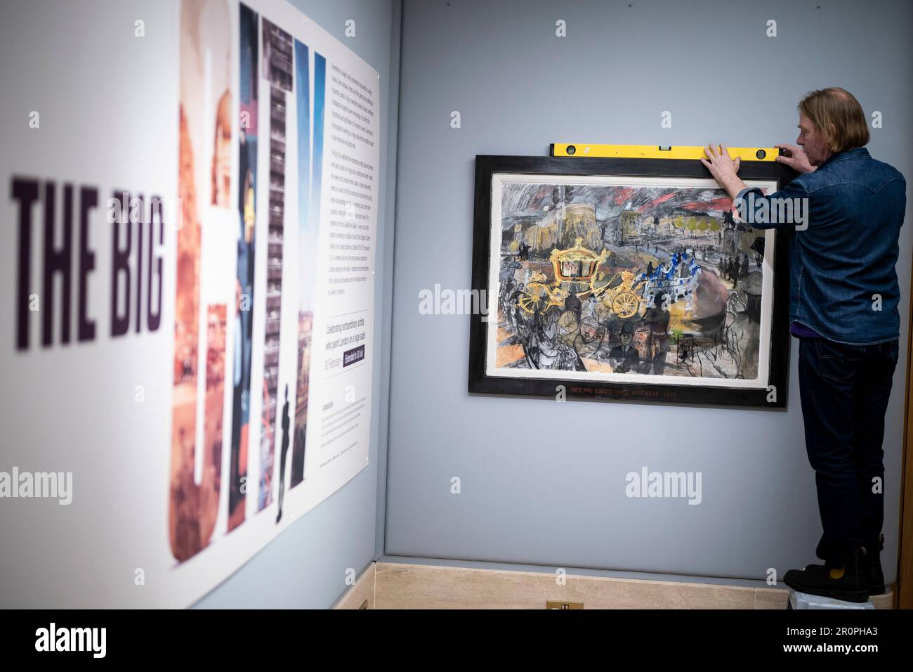 Ritrasmettendo il nome degli artisti correttori da Llewelyn a Llywelyn 'pompa e circostanza Adversus' dell'artista contemporaneo britannico, Dan Llywelyn Hall è installato nella Guildhall Art Gallery di Londra. L'illustrazione mostra che il Gold state Coach è tirato da cavalli grigi Windsor rivestiti in blu, mentre i telefoni sono tenuti in mano per scattare fotografie e video dello spettacolo che si muove oltre. Il sig. Llywelyn Hall è stato posizionato a Trafalgar Square fuori dalla National Gallery il sabato, lavorando per tutto il giorno per catturare scene della processione da Buckingham Palace all'Abbazia di Westminster. Data foto: Martedì Foto Stock