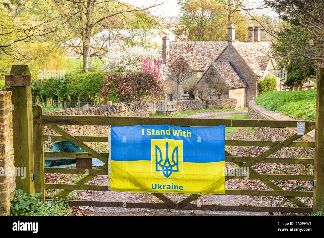 Una bandiera che mostra solidarietà con l'Ucraina sulla porta di Ducklestone Mill sul Sherborne Brook vicino al villaggio Cotswold di Sherborne, Gloucestershire Foto Stock