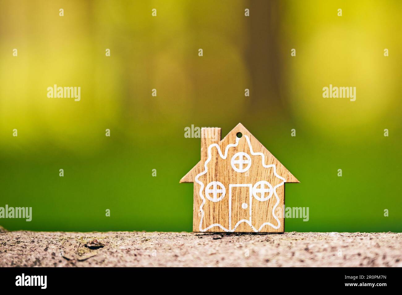 Primo piano di modello di casa in legno su sfondo verde foresta. Casa ecologica e concetto di sostenibilità. Concetto di consapevolezza ambientale mondiale. Copia Foto Stock
