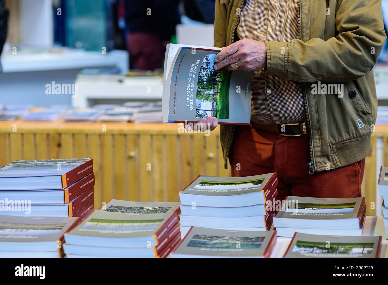 Foire du Livre de Bruxelles les gens se pressent autour des presentoirs 2023 Feuilleter un livre | Bruxelles Books fair 2023 - flipping the pages Foto Stock
