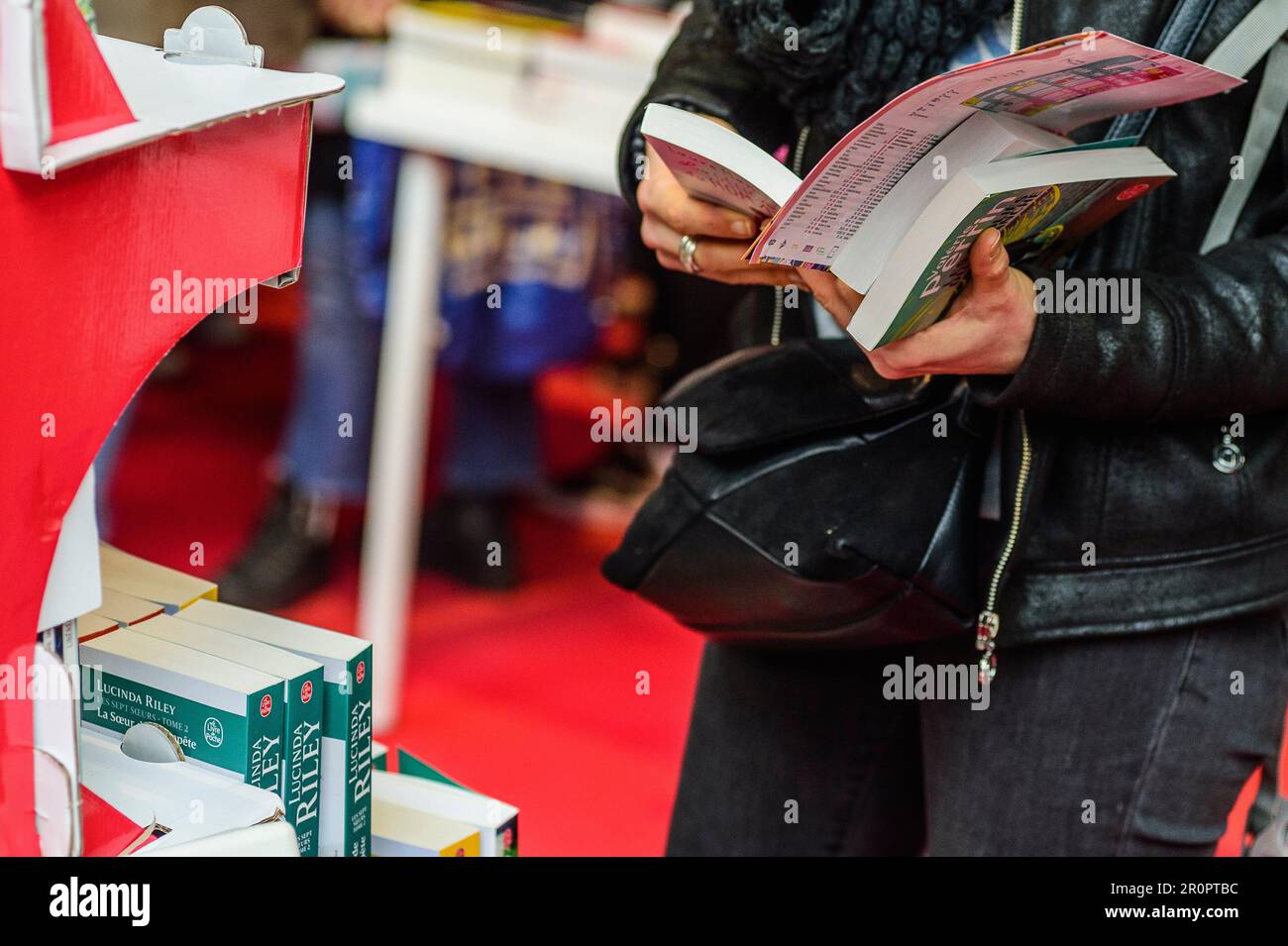 Foire du Livre de Bruxelles les gens se pressent autour des presentoirs 2023 Feuilleter un livre | Bruxelles Books fair 2023 - flipping the pages Foto Stock