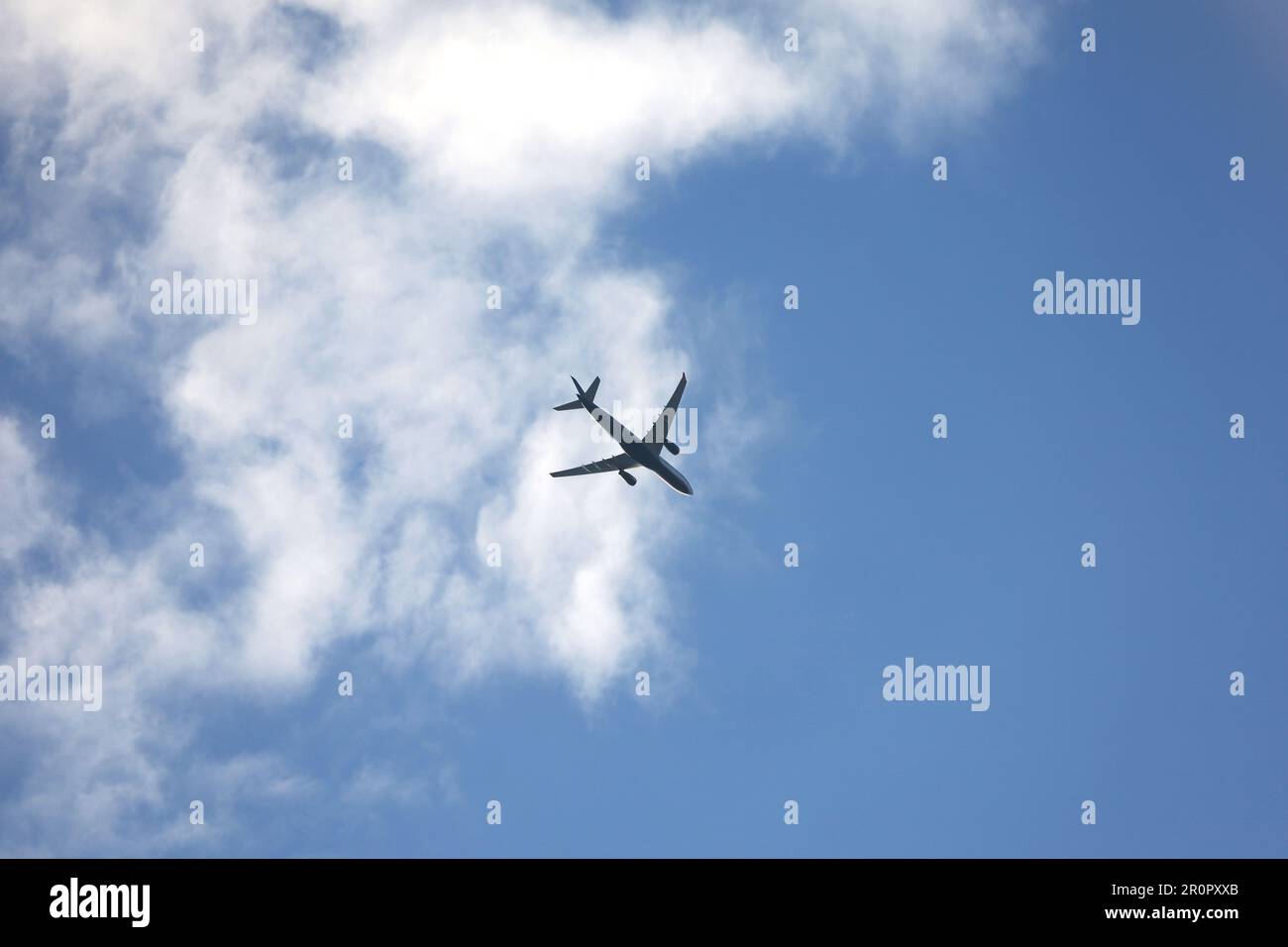 Silhouette di aeroplano che vola in cielo con nuvole bianche. Aereo passeggeri in volo, concetto di viaggio Foto Stock