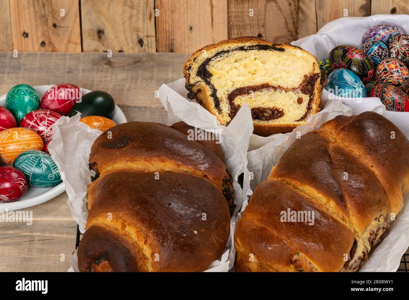 Torte rumene appena sfornate e uova di Pasqua dipinte a mano. 'Cozonaca' o 'cozonaci', è fatto di pasta di lievito dolce usata per fare holi tradizionali Foto Stock